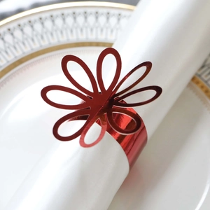 Detail of red hollow flower napkin ring with mirror finish on a white dinner plate