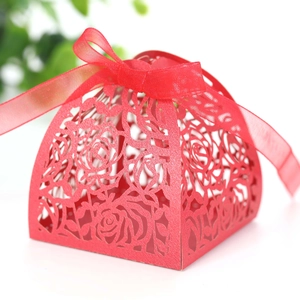 Close-up of red laser-cut wedding favor box with rose patterns and a silk ribbon bow
