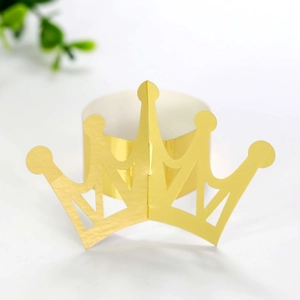 Detail of a shiny gold crown napkin ring with hollow patterns for party table decoration
