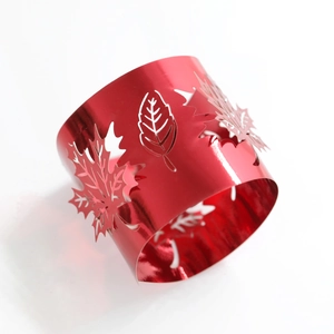 Detail of red hollow leaf napkin ring showing laser-cut maple leaf patterns on metal