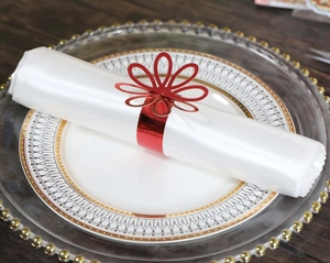 Detailed view of red hollow flower napkin ring on white satin fabric over luxury tableware