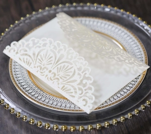 Detailed laser-cut lace pattern on white glitter wedding invitation on elegant dinner plate