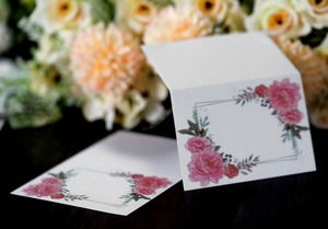 Detail showing white rose place cards with elegant floral patterns for wedding tables