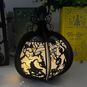 Halloween pumpkin silhouette lantern with witch and cat cutouts emitting warm yellow light