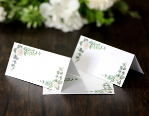 Close-up of floral place cards with rose patterns on a textured wooden background