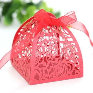 Detail of red laser-cut wedding favor box with rose patterns and organza ribbon bow