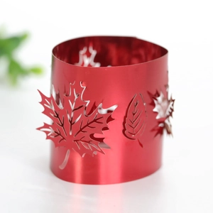 Macro detail of red maple leaf cutout metal napkin ring on minimalist white background