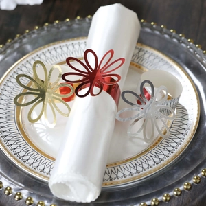 Close-up of elegant flower napkin rings in gold, silver, and red for wedding table decor