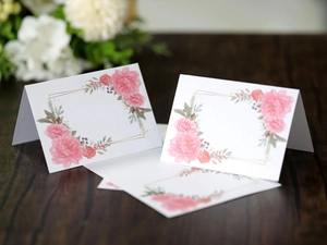 Elegant floral place card with pink roses and gold frame on dark wood for weddings