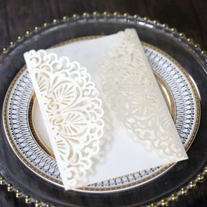 Detail of laser-cut lace wedding invitation with gold glitter and elegant floral hollow pattern
