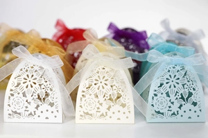 Detail of laser cut flower patterns on wedding favor candy boxes with organza ribbons