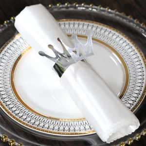 Close-up of crown silver napkin ring on a white silk napkin and elegant china plate