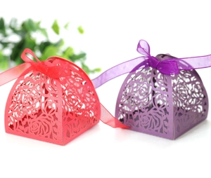 Macro detail of laser-cut rose hollow gift boxes in red and purple with silk ribbons