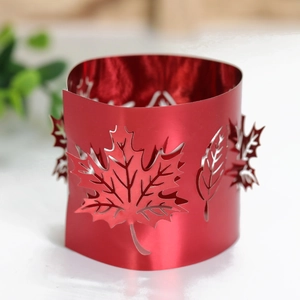 Detail of red metal candle sleeve featuring laser-cut maple leaf hollow patterns