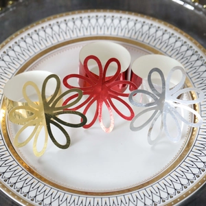 Detailed close-up of hollow petal napkin rings in gold, red, and silver finishes