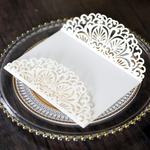 Detail of laser-cut lace invitation cover with pearlescent glitter on a glass plate