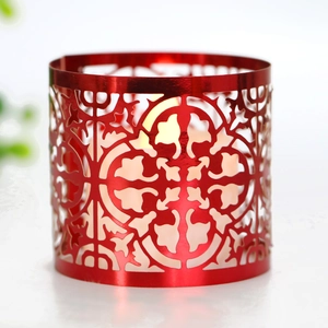 Macro detail of red laser-cut metal candle holder with intricate floral patterns