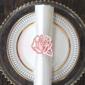 Detail of pink laser-cut rose paper napkin ring on a white napkin for wedding decor