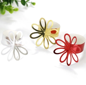 Close-up of gold, silver, and red floral paper napkin rings for wedding table decoration