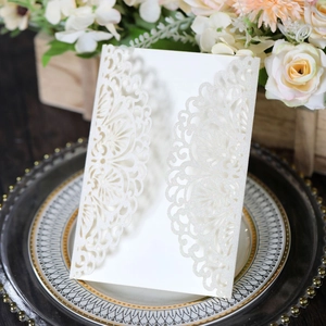 Detail of laser-cut wedding invitation with white glitter texture on a vintage gold tray