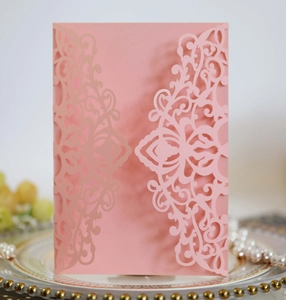 Intricate laser-cut pink pearlescent invitation sleeve with elegant floral patterns