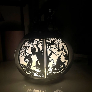 Detail of Halloween paper lantern with warm light and intricate black cutout patterns