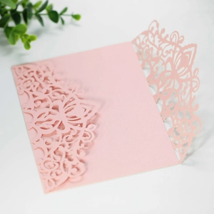 Macro view of laser-cut pink wedding invitation cover with intricate floral pattern