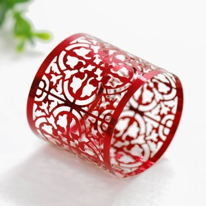 Detail of red hollow laser-cut napkin ring with intricate floral pattern on white background