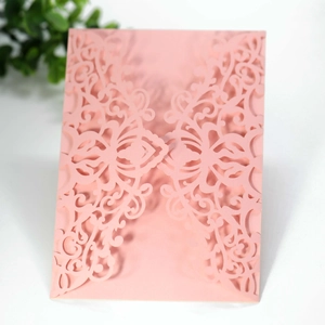 Close-up of pink laser-cut wedding invitation card with intricate floral hollow design
