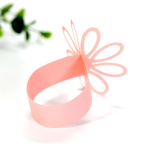 Detail showing laser-cut pink paper flower napkin ring with elegant petal butterfly design