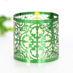 Detail of laser-cut green metal lantern showing elegant scroll patterns and warm LED light