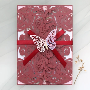 Detailed laser-cut wine red wedding invitation with white butterfly and red ribbon