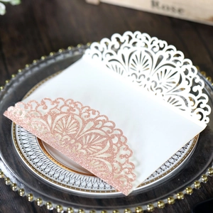 Detail of white laser cut invitation with rose gold glitter European lace pattern