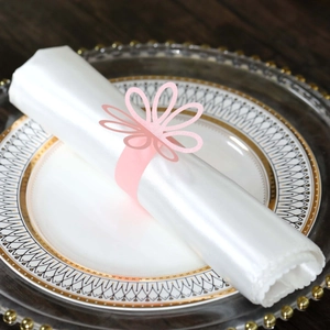 Close-up of a pink hollow flower napkin ring on white satin fabric for wedding table decor