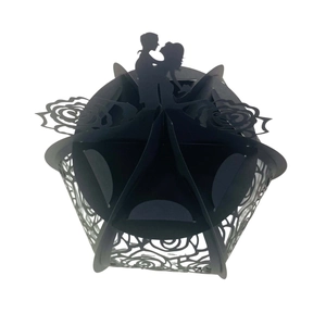 Detail of laser-cut black paper cupcake wrapper with rose patterns and couple silhouette