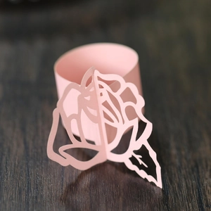 Macro shot of pink pearl paper napkin ring with laser-cut rose detail on wood background