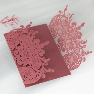 Detail of laser-cut burgundy wedding invitation with intricate floral hollowed patterns