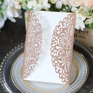 Macro view of rose gold glitter laser-cut invitation featuring intricate mandala floral patterns