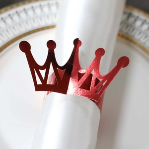 Detail of red metallic crown napkin ring with reflective finish on a white dinner plate