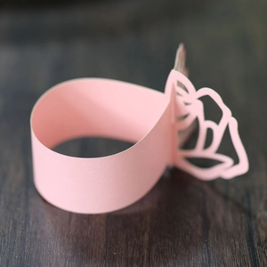 Macro view of pink hollowed-out paper napkin rings with elegant floral cutout design