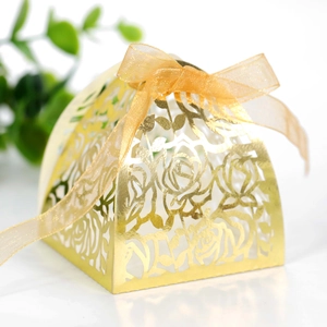 Close-up of golden laser-cut rose hollow candy box with orange organza ribbon bow