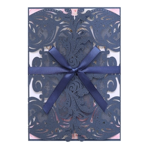 Macro view of blue laser-cut wedding invitation featuring ribbon bow and floral card