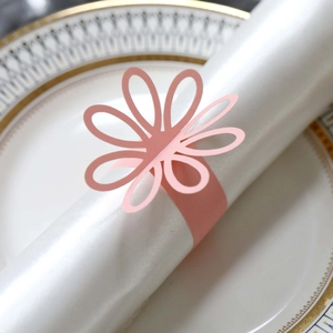 Detail of laser-cut pink paper flower napkin ring on elegant white dinnerware