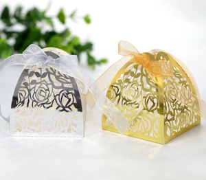Detail of hollow laser-cut rose candy boxes in gold and silver with elegant ribbon bows