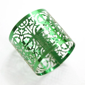 Macro detail of metallic green hollow-out napkin ring with intricate laser-cut patterns