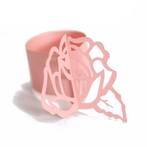 Detail of pink laser-cut paper napkin rings with 3D rose flower pattern for weddings