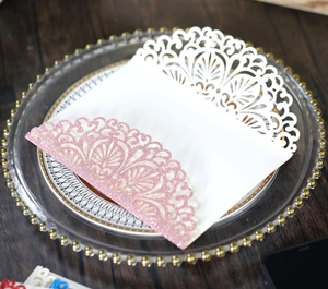 Detailed laser-cut lace pattern on pearl white wedding invitation with pink glitter finish