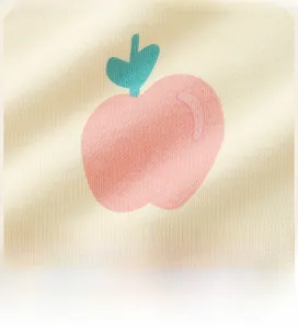 Close-up of light yellow knit fabric featuring a cute pink cartoon apple print