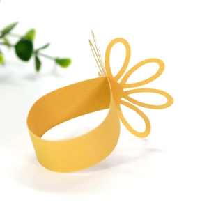 Detailed view of hollow petal design on gold paper napkin rings for table settings