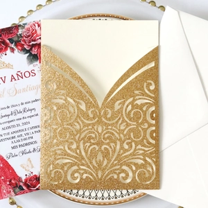 Detail of glitter gold laser cut invitation with floral patterns and cream inner card